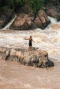 Laos fisherman standing on the rock in rapids of Li Phi Waterfall. Li Phi Waterfall is one of the highlights of the 4,000 Islands